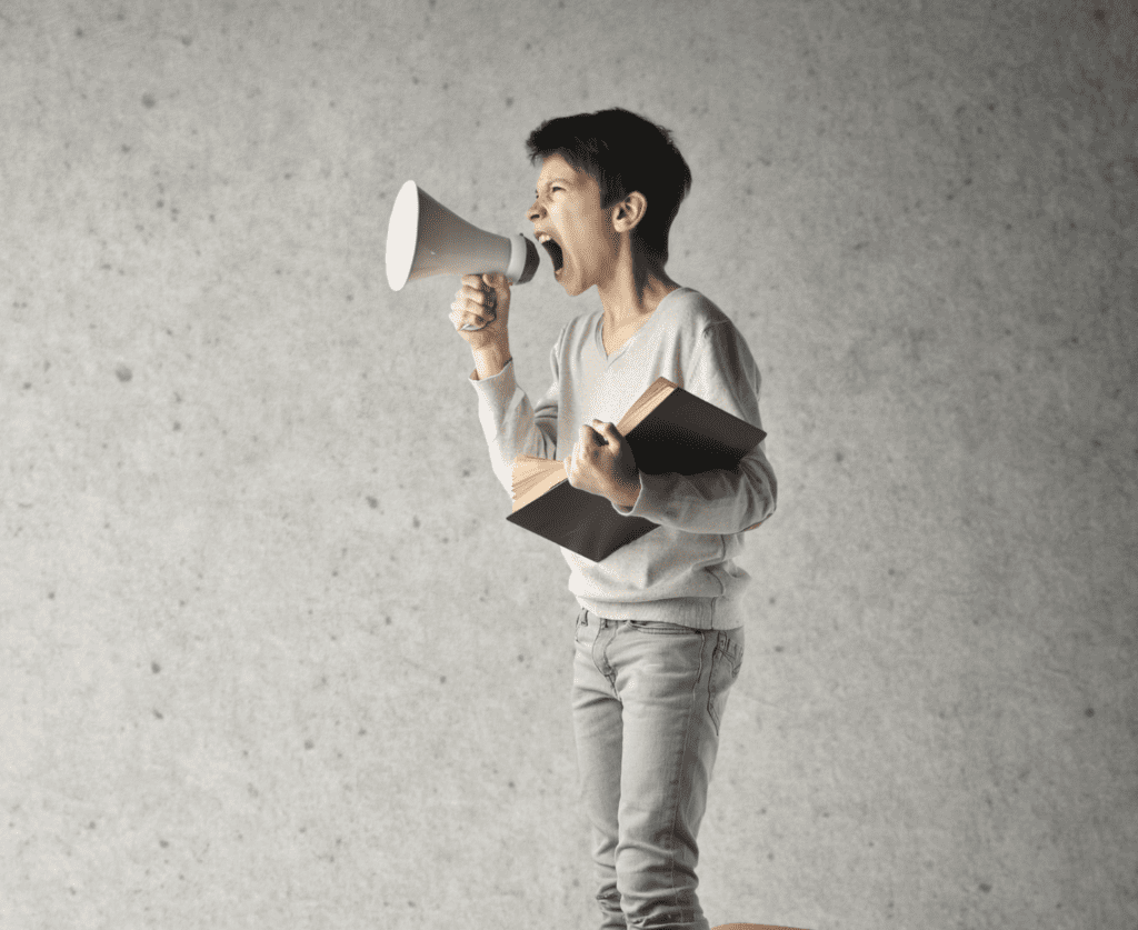 A male kid holding a book and megaphone shouting