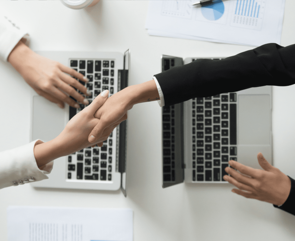 Hand shake between two professional while using their laptop