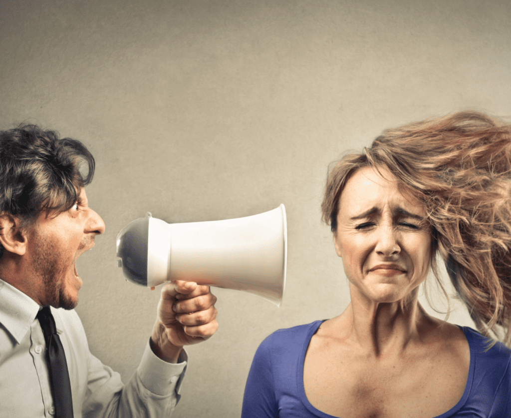 A man holding a megaphone screaming to a lady beside with her hair flying to the side