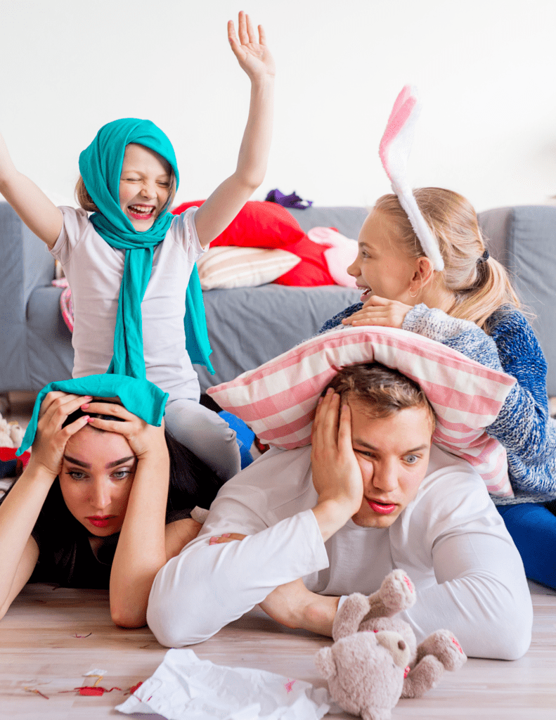 Parents Looking Overwhelmed With Two Kids Playing On Top Of Them