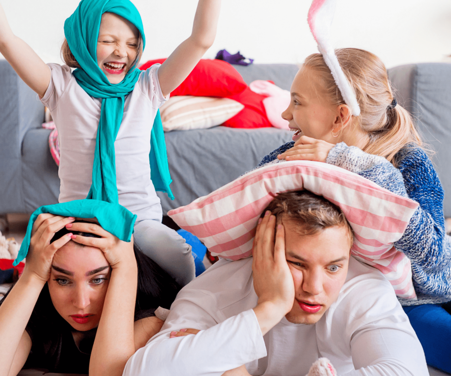 Parents Looking Overwhelmed With Two Kids Playing On Top Of Them